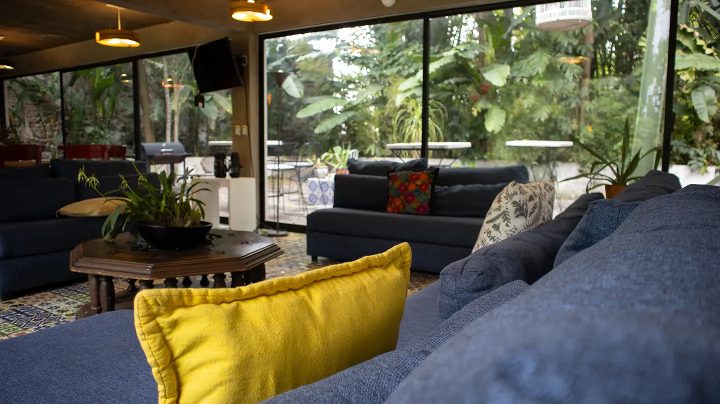 Sala con sofá azul y cojín amarillo frente a ventanales