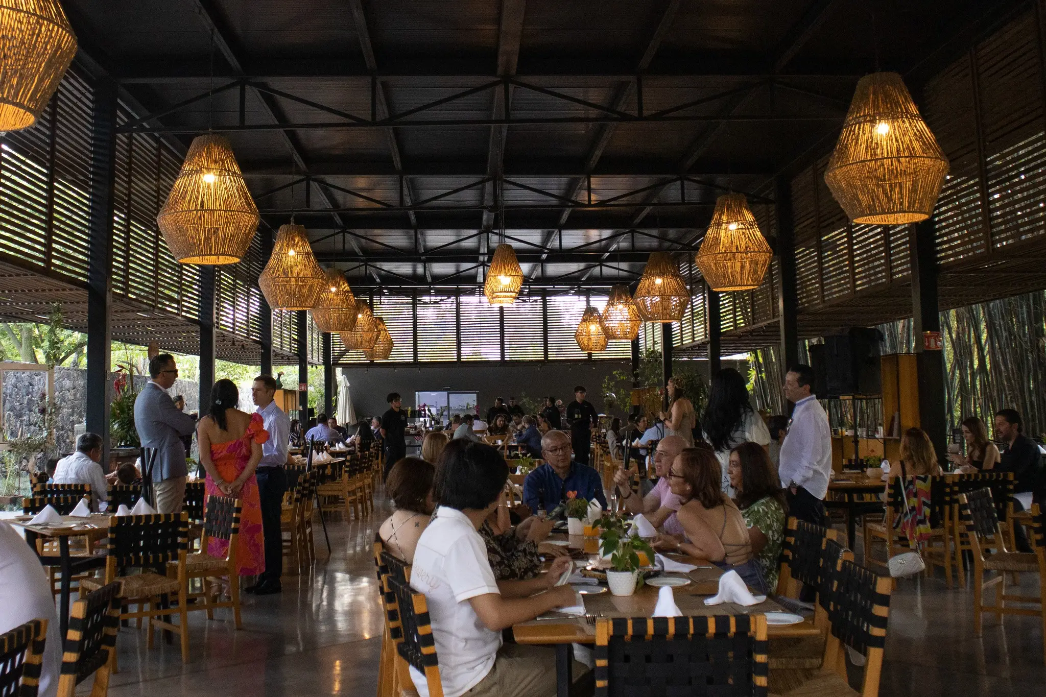 Restaurante con comensales bajo lámparas de palma tejida